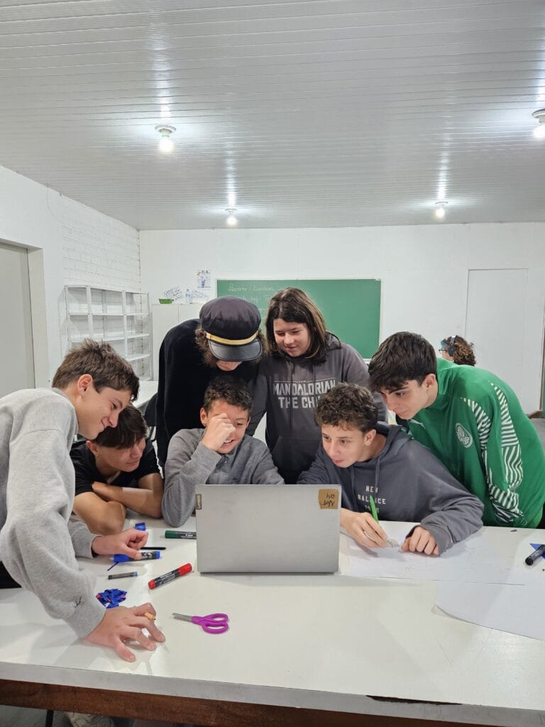 Estudantes reunidos em volta de um computador